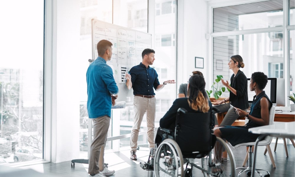 Image featuring a diverse group of employees collaborating in a modern office space, reflecting the importance of diversity, equity, and inclusion in the workplace.